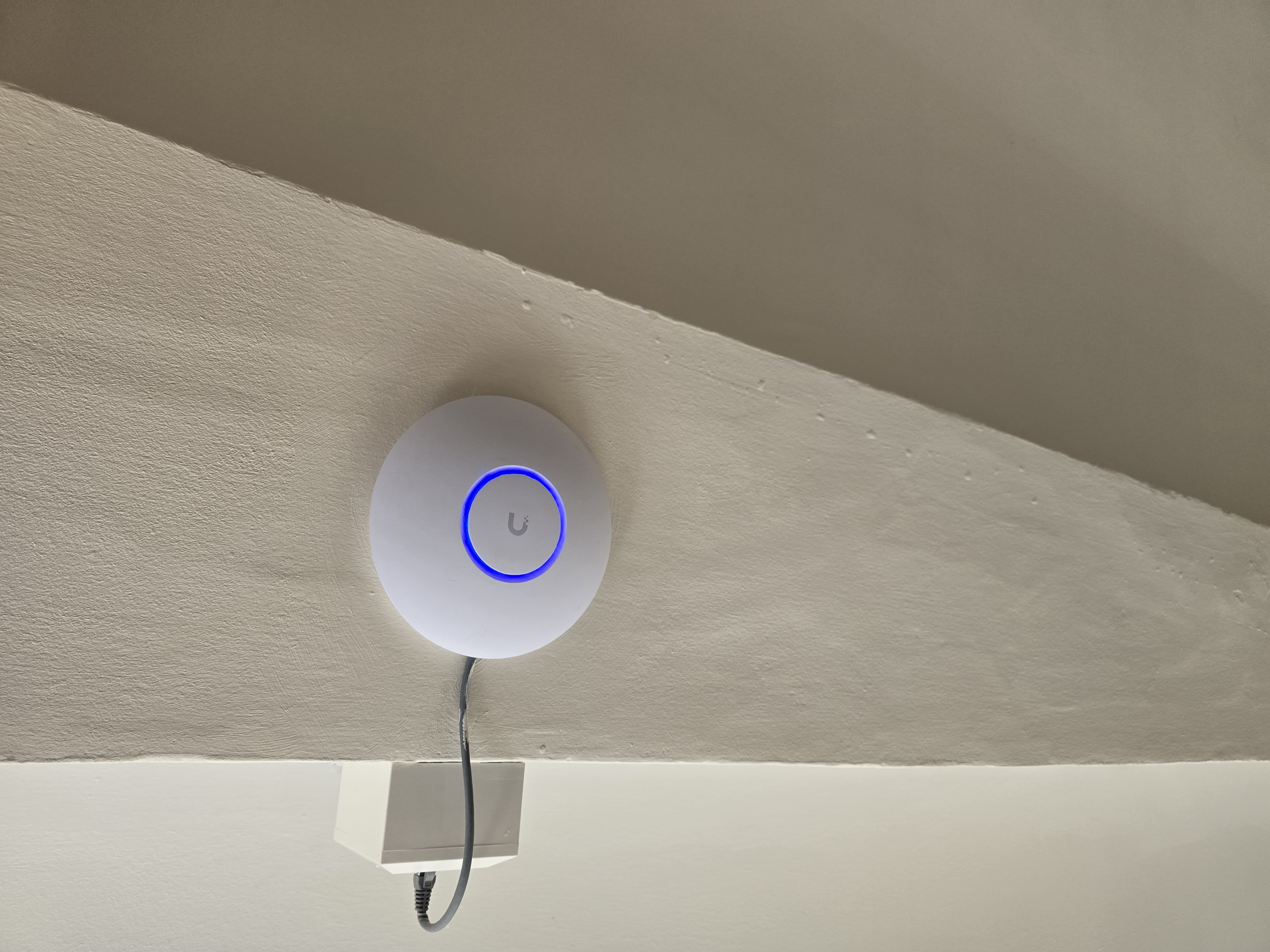 UniFi access point mounted below a sloped ceiling during the care home WiFi upgrade
